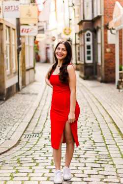 Ganzkörper-Portrait einer jungen Frau mit dunklen Haaren und rotem Kleid in einer Straße des Schnoor-Viertel Bremen